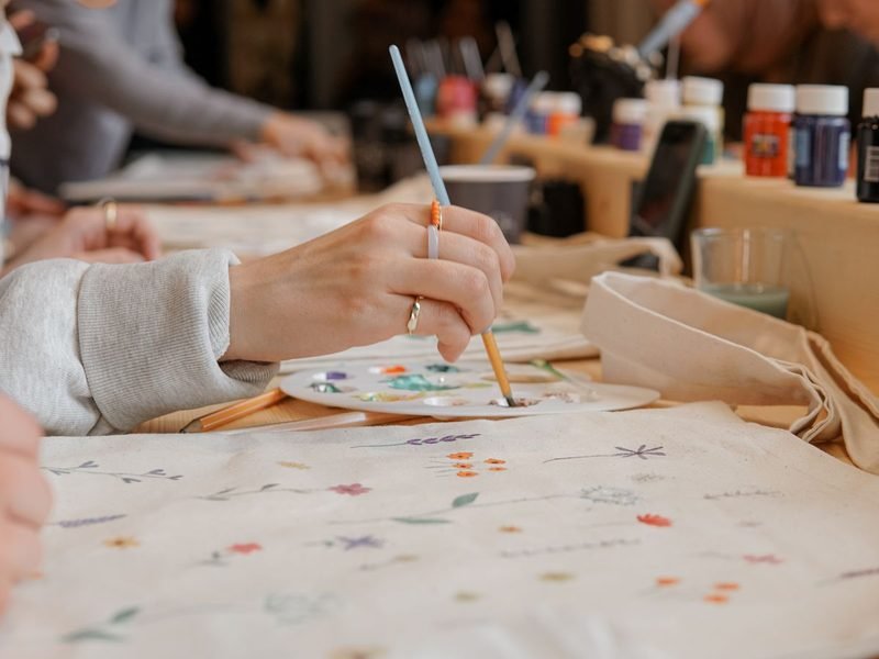 Personas pintando tote bags en un taller